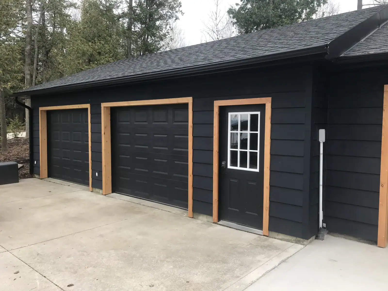 Black-sided garage with wood-trimmed doors