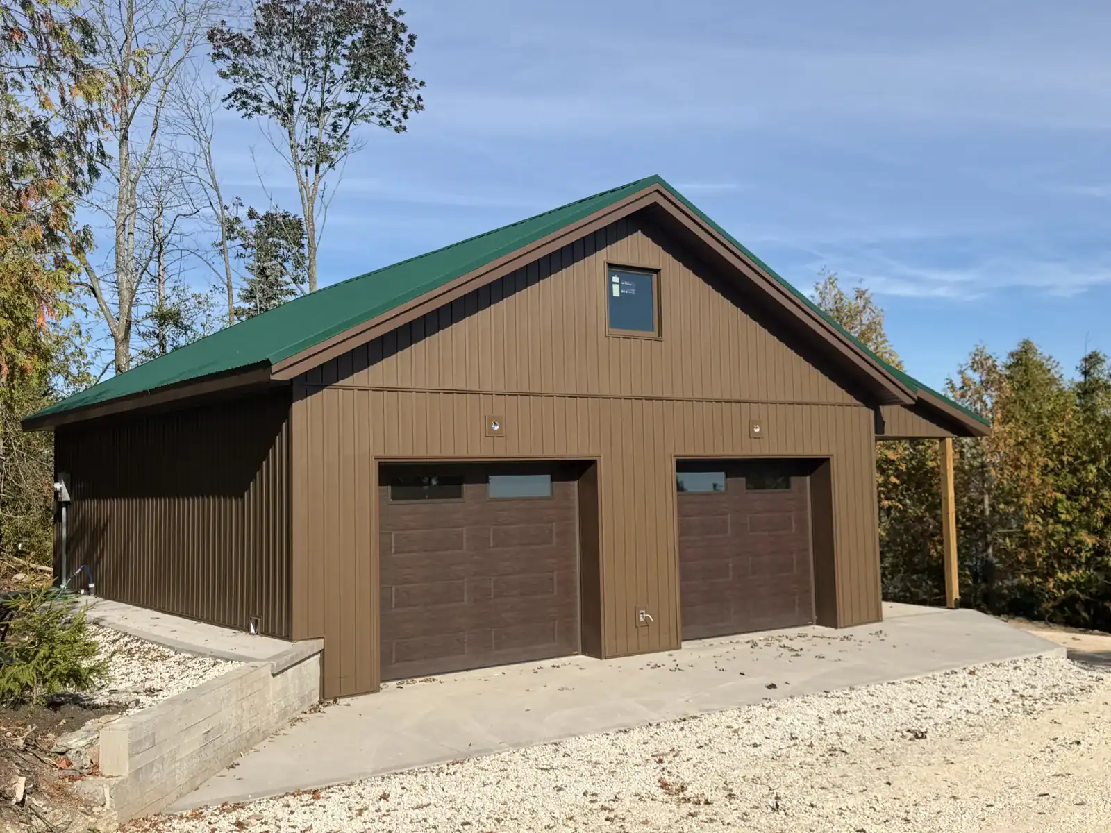 Finished two-door garage with brown board-and-batten siding and green metal roof
