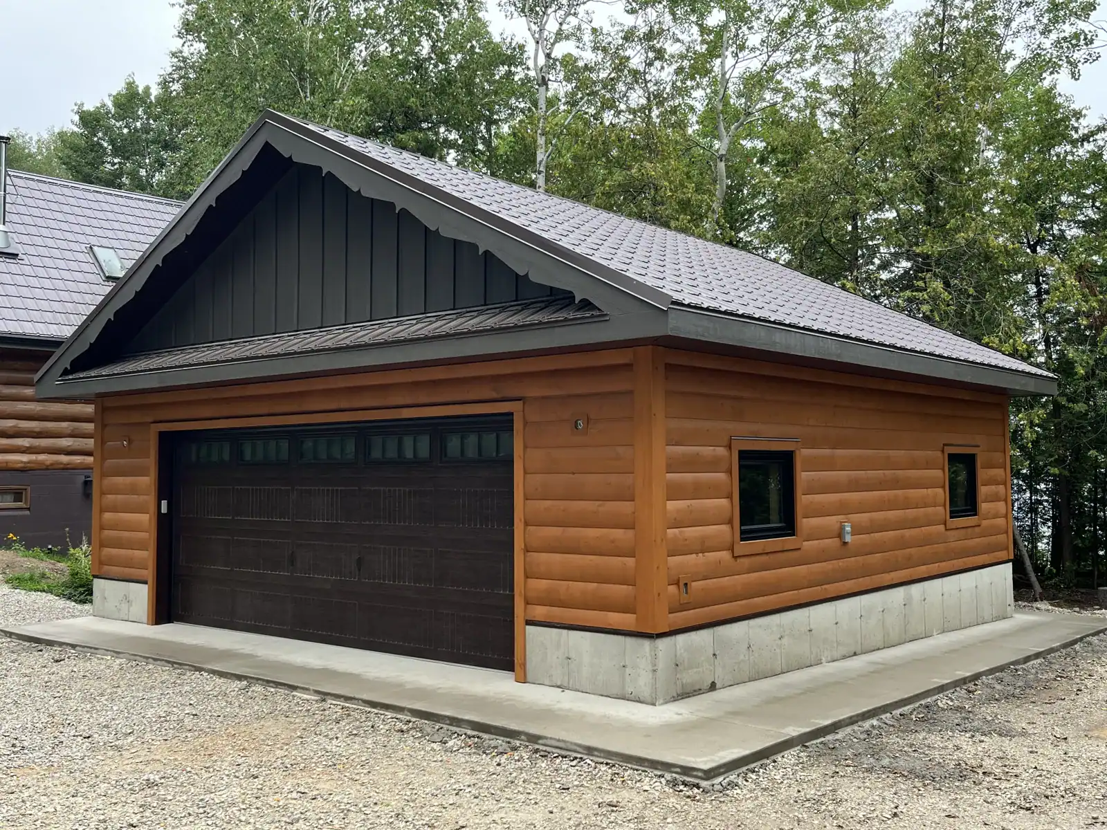 Log-sided garage with metal roof and concrete apron