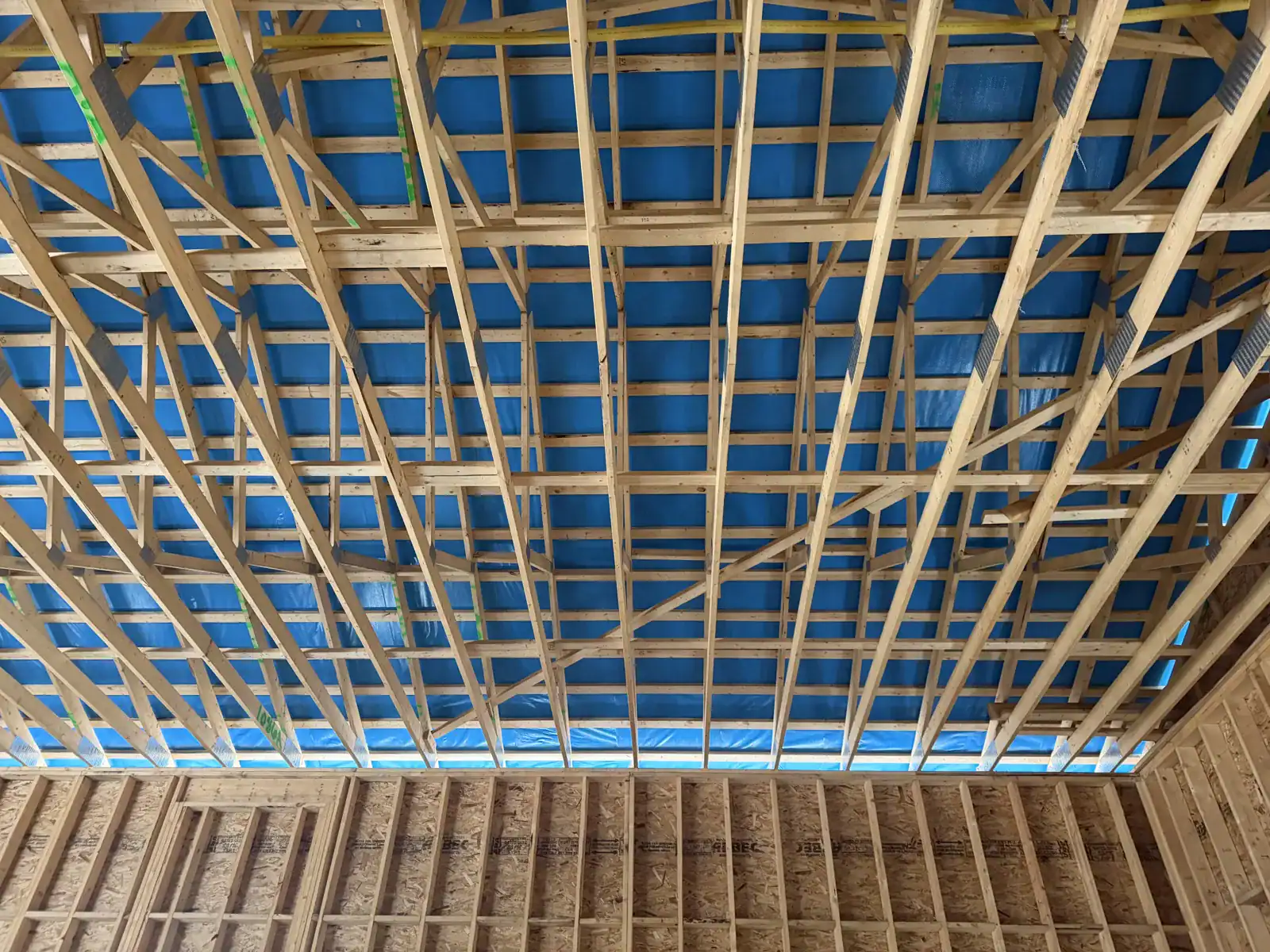 Roof strapping and framing seen from inside against a blue sky