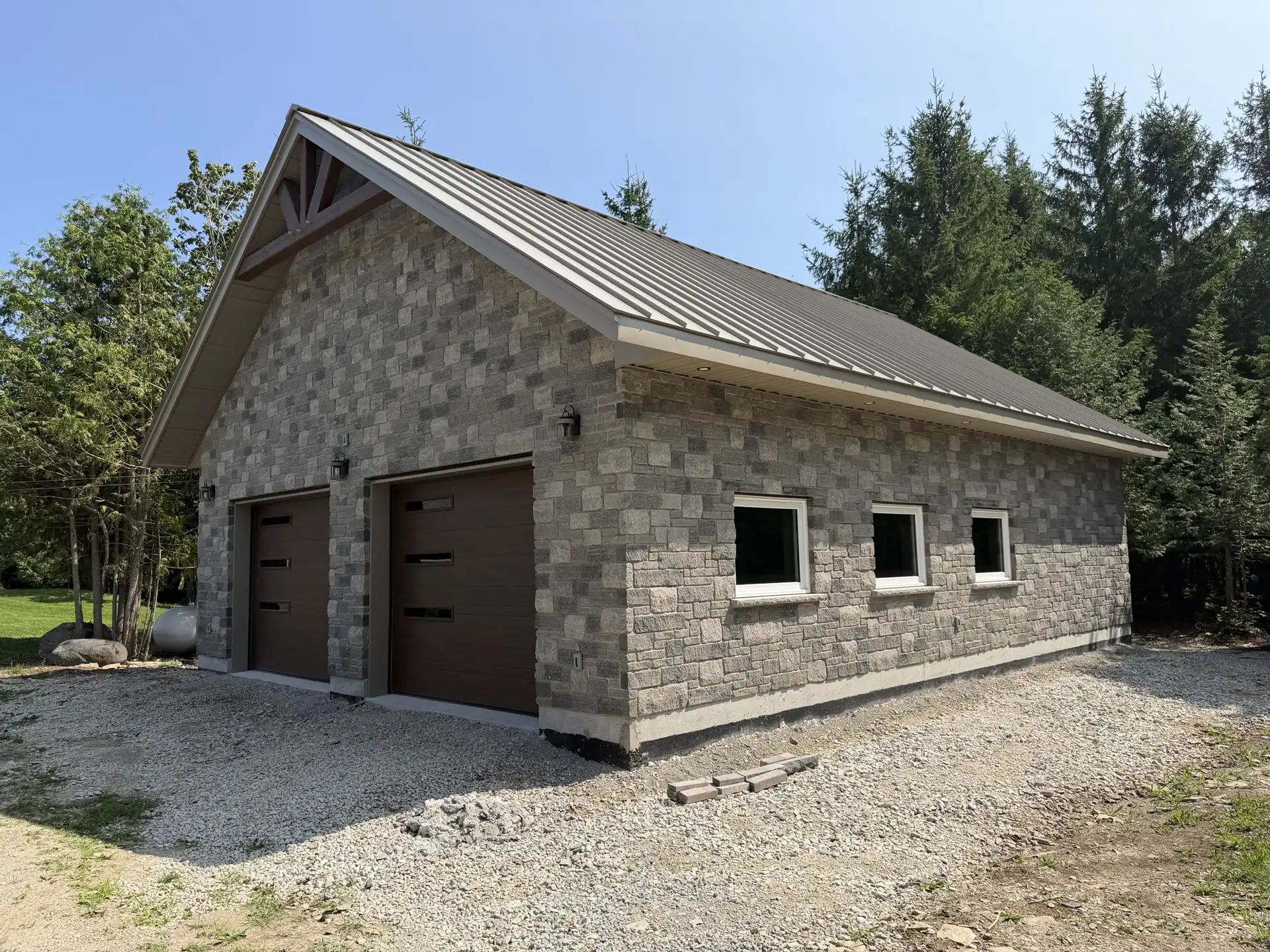 Stone-clad garage with timber gable and standing seam roof