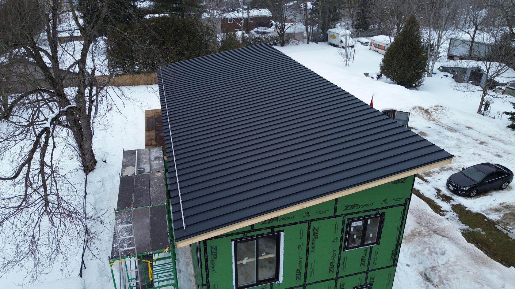 Matte black standing seam metal roof, winter drone view