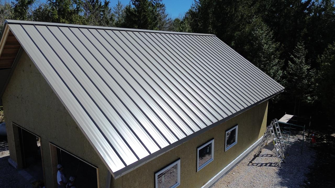 Bone white standing seam roof and matching wall panels on a garage in the sun