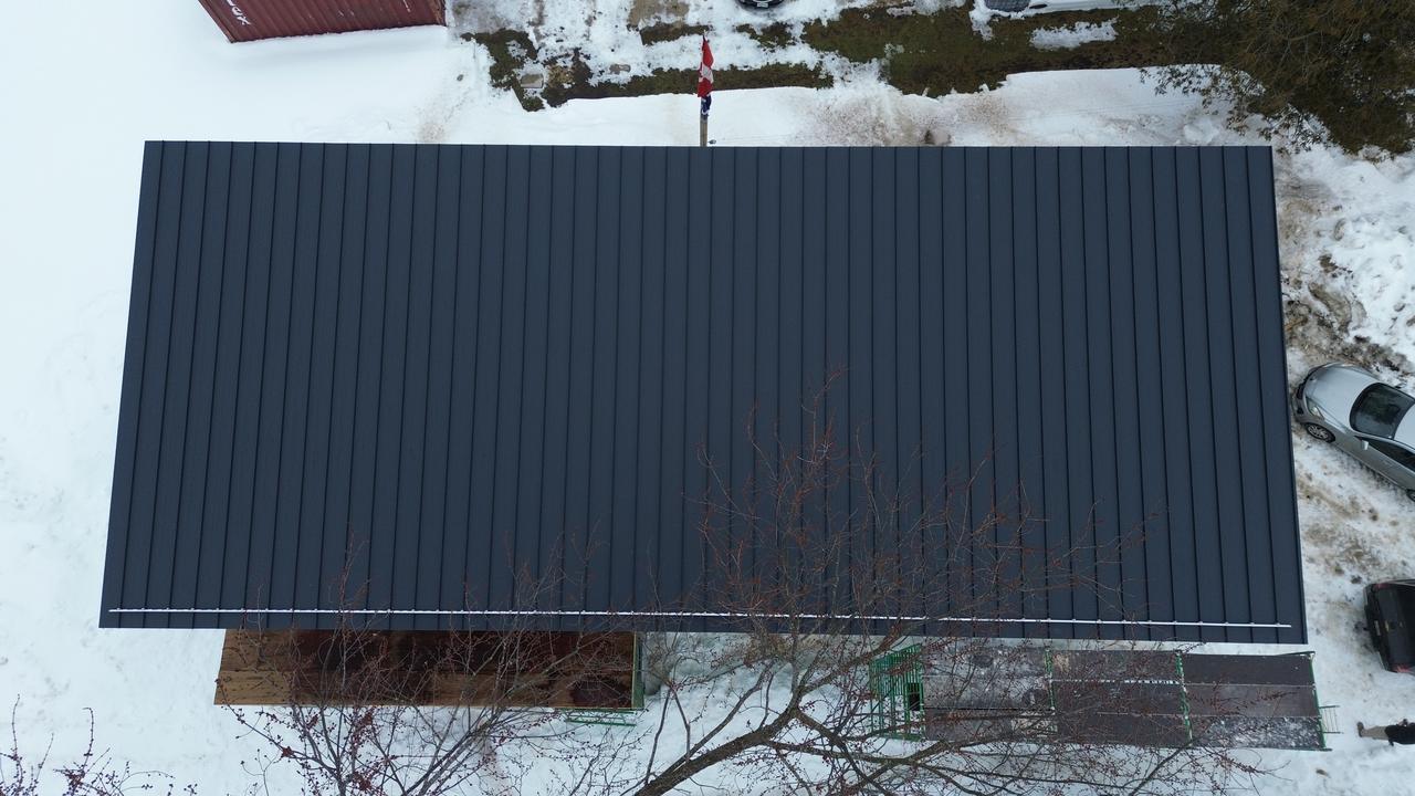 Top-down drone view of a matte black standing seam roof