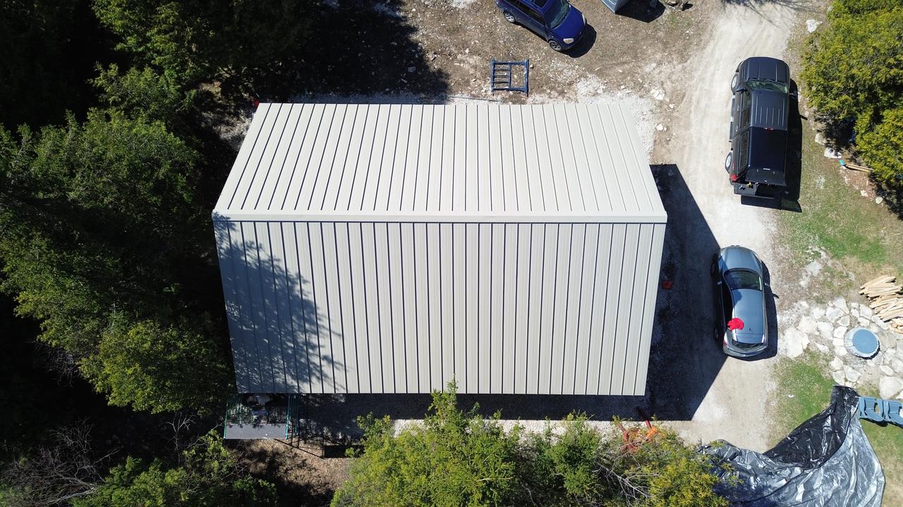 Top-down drone view of bone white standing seam roof and wall panels